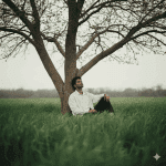 A beautiful bride in a flowing white wedding gown with a lace open back, turning on a terracotta balcony, surrounded by planters of red roses, overlooking the rolling hills of a Tuscan or Italian landscape at sunset.