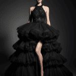 Haute couture black evening gown with dramatic tiered tulle layers and a sparkling beaded halter bodice, modeled in a minimalist studio with moody lighting