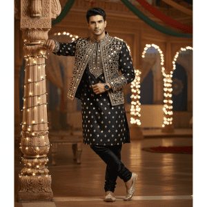 A handsome, laughing man with a modern haircut, wearing a burgundy velvet blazer, stands next to a vintage cream-colored convertible car, holding a large, colorful bouquet of roses and lilies.