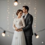 "Full-body pre-wedding portrait of a couple, girl in elegant flowing lace bridal-style dress smiling softly, boy in dark suit gently kissing her forehead, minimalistic warm background, capturing romance and intimacy."