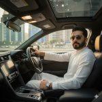 Ultra-realistic 8K cinematic photo of a confident person wearing a white salwar kameez, silver watch, and sunglasses, sitting in the driver’s seat of a Honda Civic at night. Dashboard lights illuminate the face, with glowing Islamabad city lights visible through the windows.